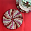 Peppermint patterned rattan charger/placemat on a red background.