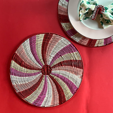 Peppermint patterned rattan charger/placemat on a red background.