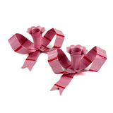 Two pink decorative bow candle holders with red stripes on a white background
