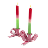 set of pink bow-shaped candleholders with lit red and green taper candles