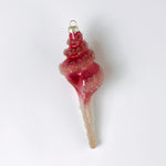 Decorative pink glass Christmas ornament shaped like a conch shell on a white background