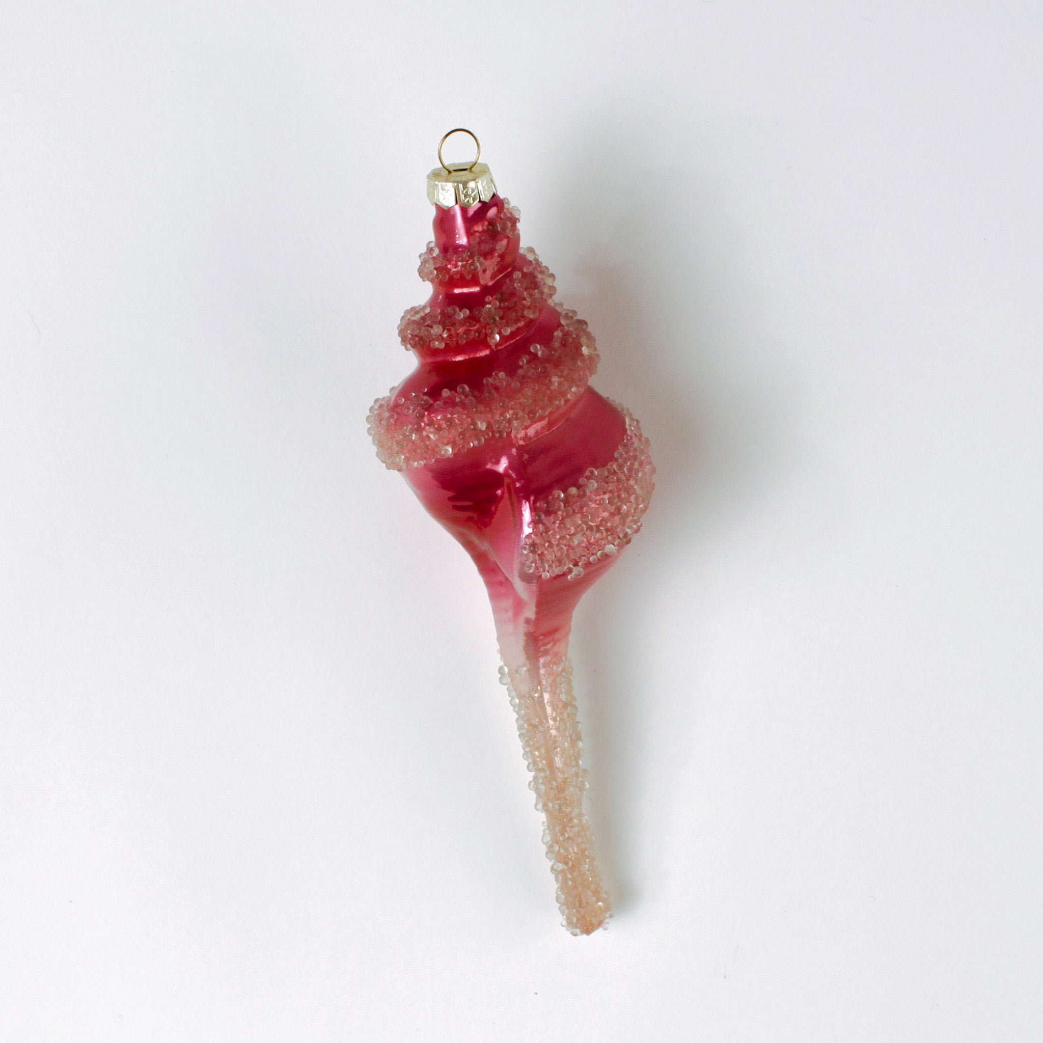Decorative pink glass Christmas ornament shaped like a conch shell on a white background