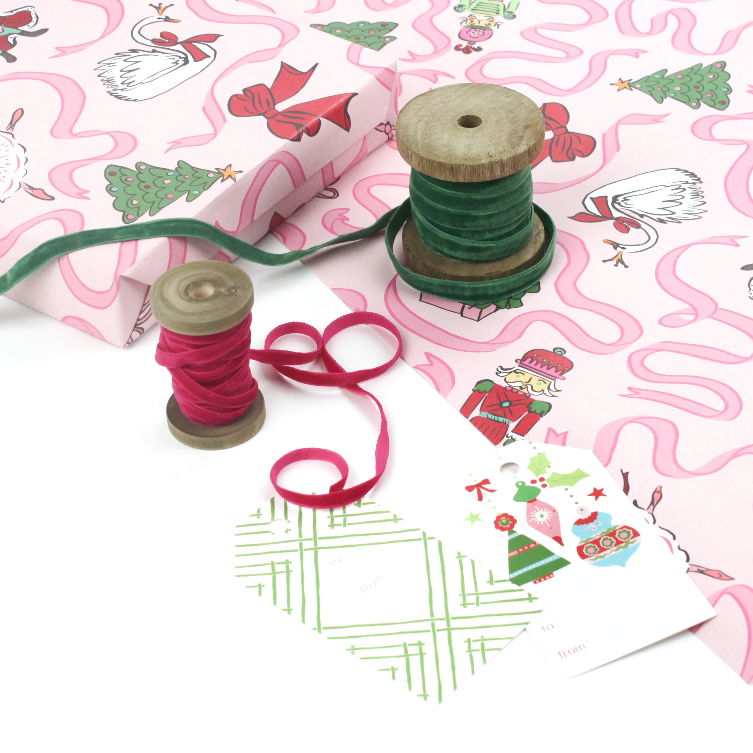 Pink nutcracker Christmas wrapping paper displayed with green and pink velvet ribbons and holiday gift tags.