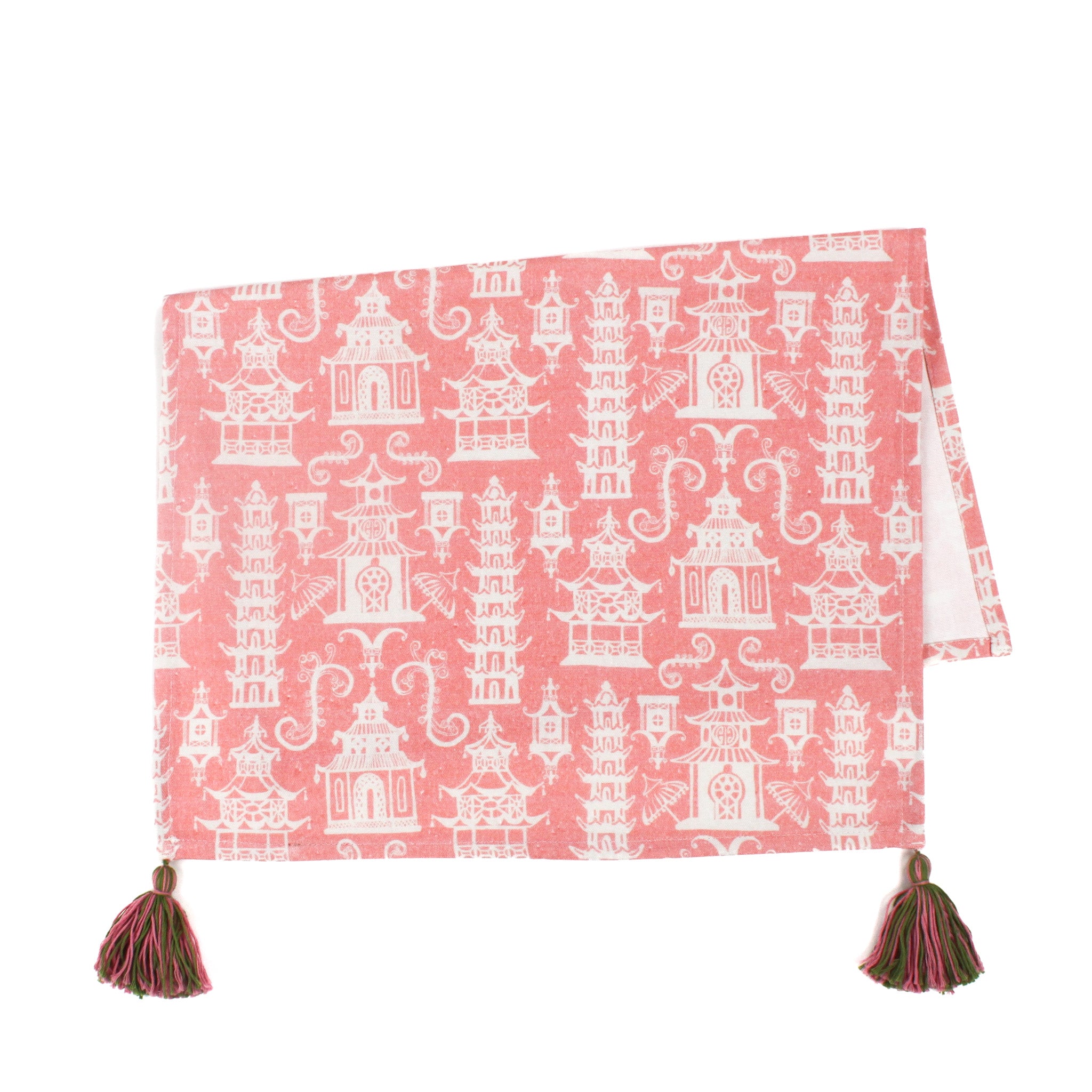 a pink chinoiserie tea towel with white pagodas and green and pink tassels in the corner resting on a white background. 