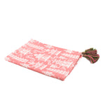 a pink chinoiserie tea towel with white pagodas and green and pink tassels in the corner resting on a white background. 