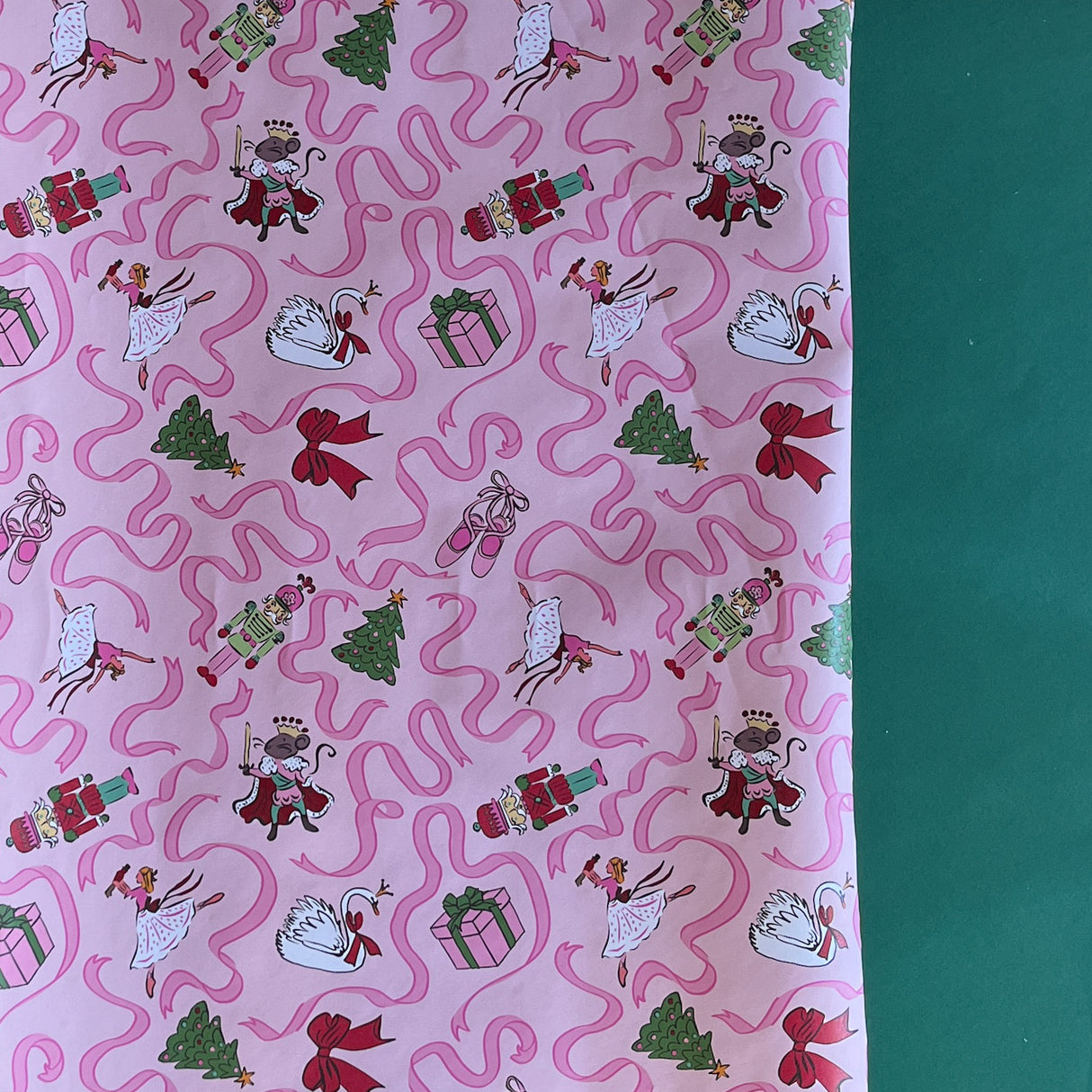 Pink Christmas wrapping paper featuring ribbons, nutcracker, ballerina and christmas tree motifs