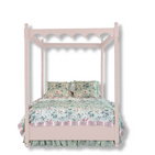 A pink canopy bed with floral bedding. 