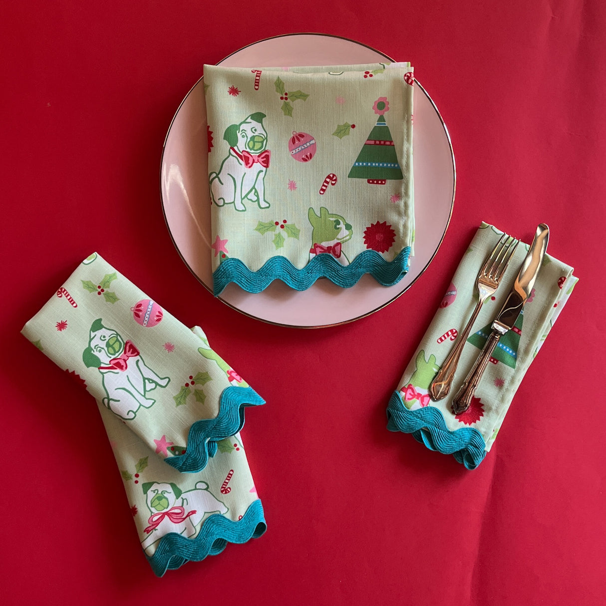 Pug Perfection Christmas Cloth Dinner Napkins on a pink plate with cutlery
