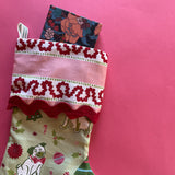 A green Christmas stocking with pug motifs and a pink striped top