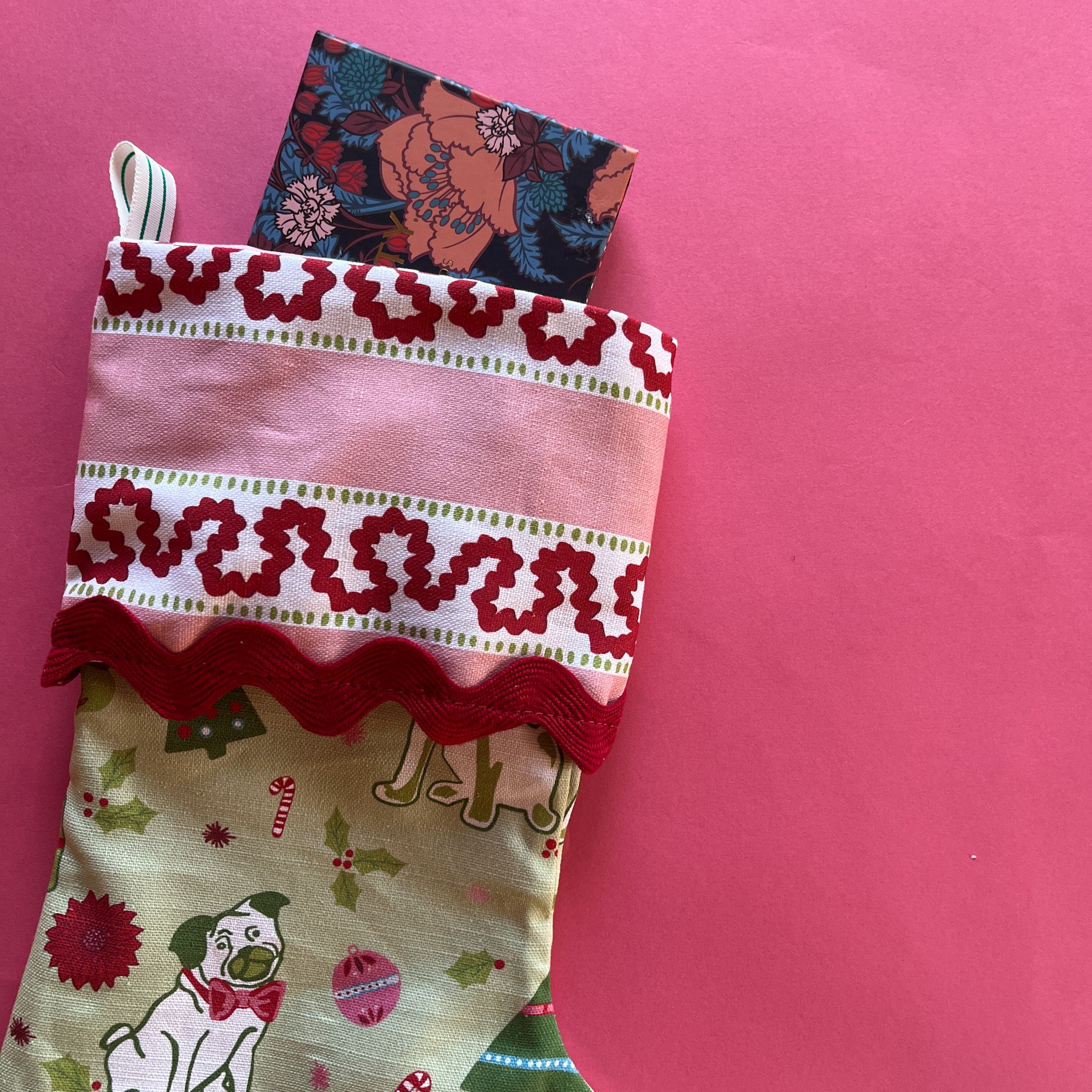 A green Christmas stocking with pug motifs and a pink striped top
