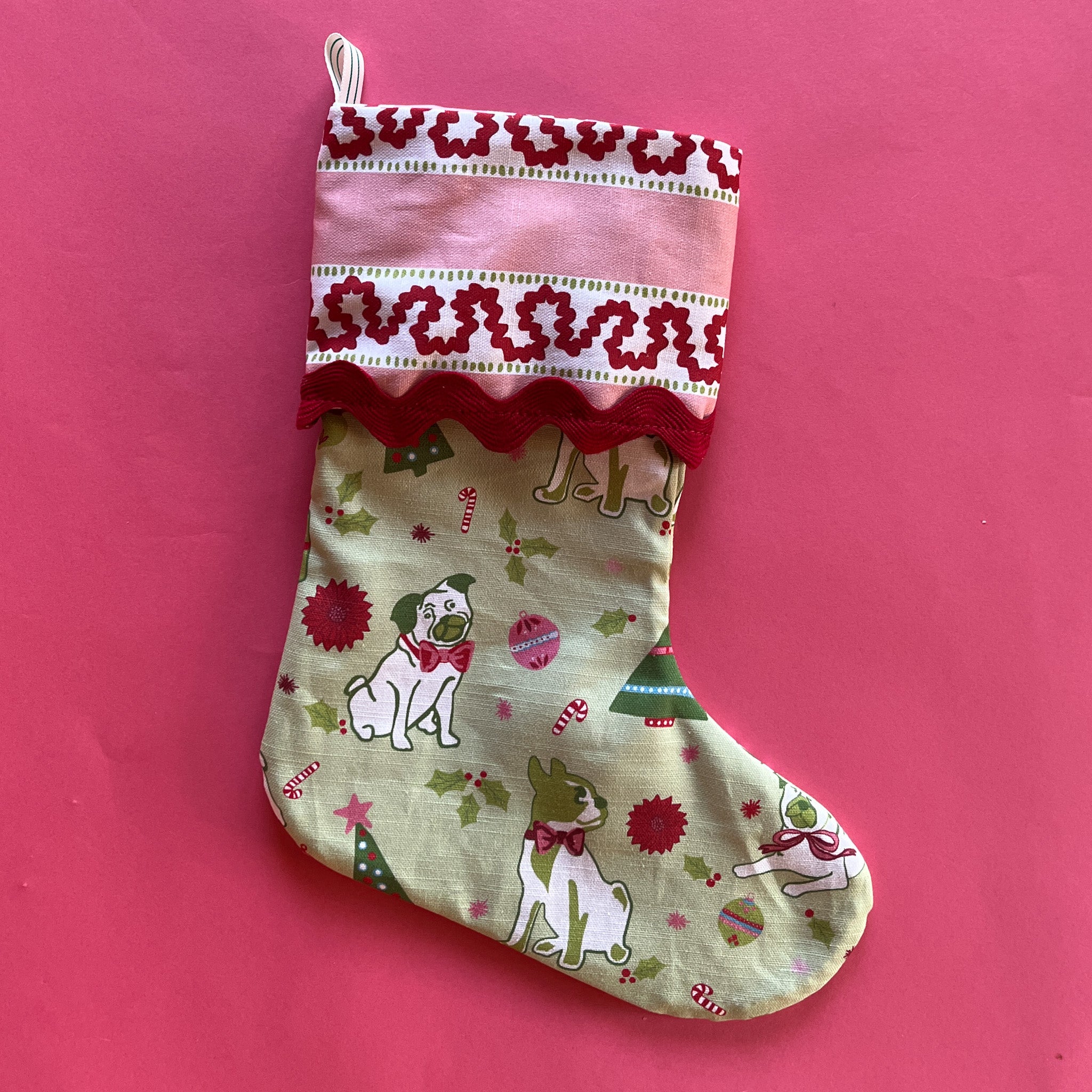 A green Christmas stocking with pug motifs and a pink striped top