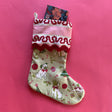 A green Christmas stocking with pug motifs and a pink striped top