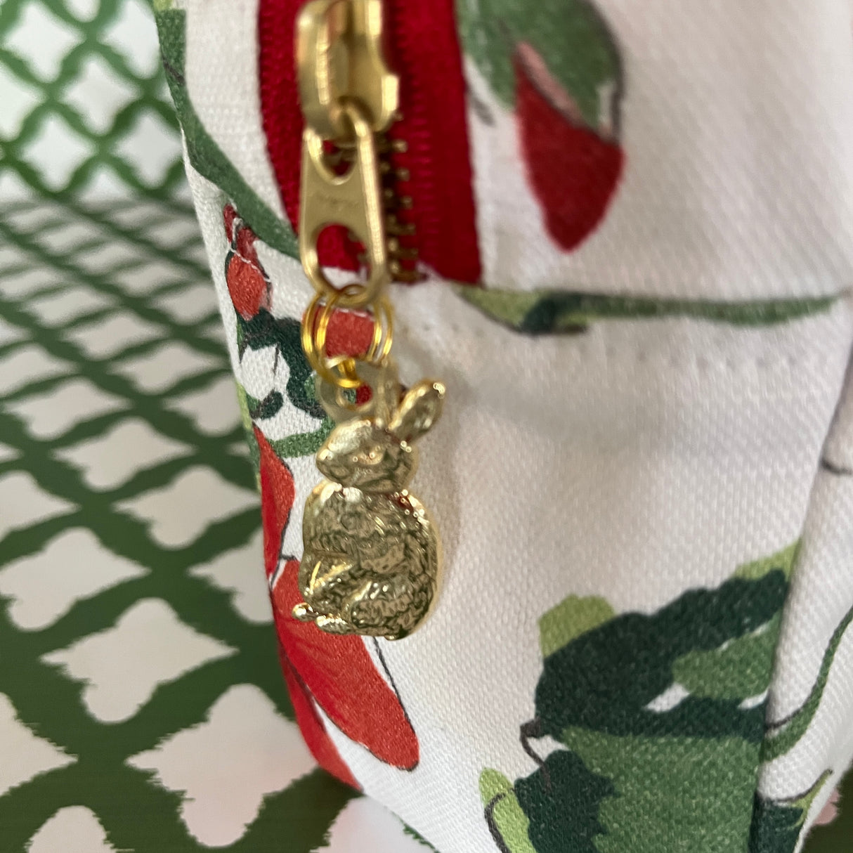 Pull detail of Cottage Grove Geranium is a floral toiletries bag with a red, green, and white color scheme, featuring a geranium design.