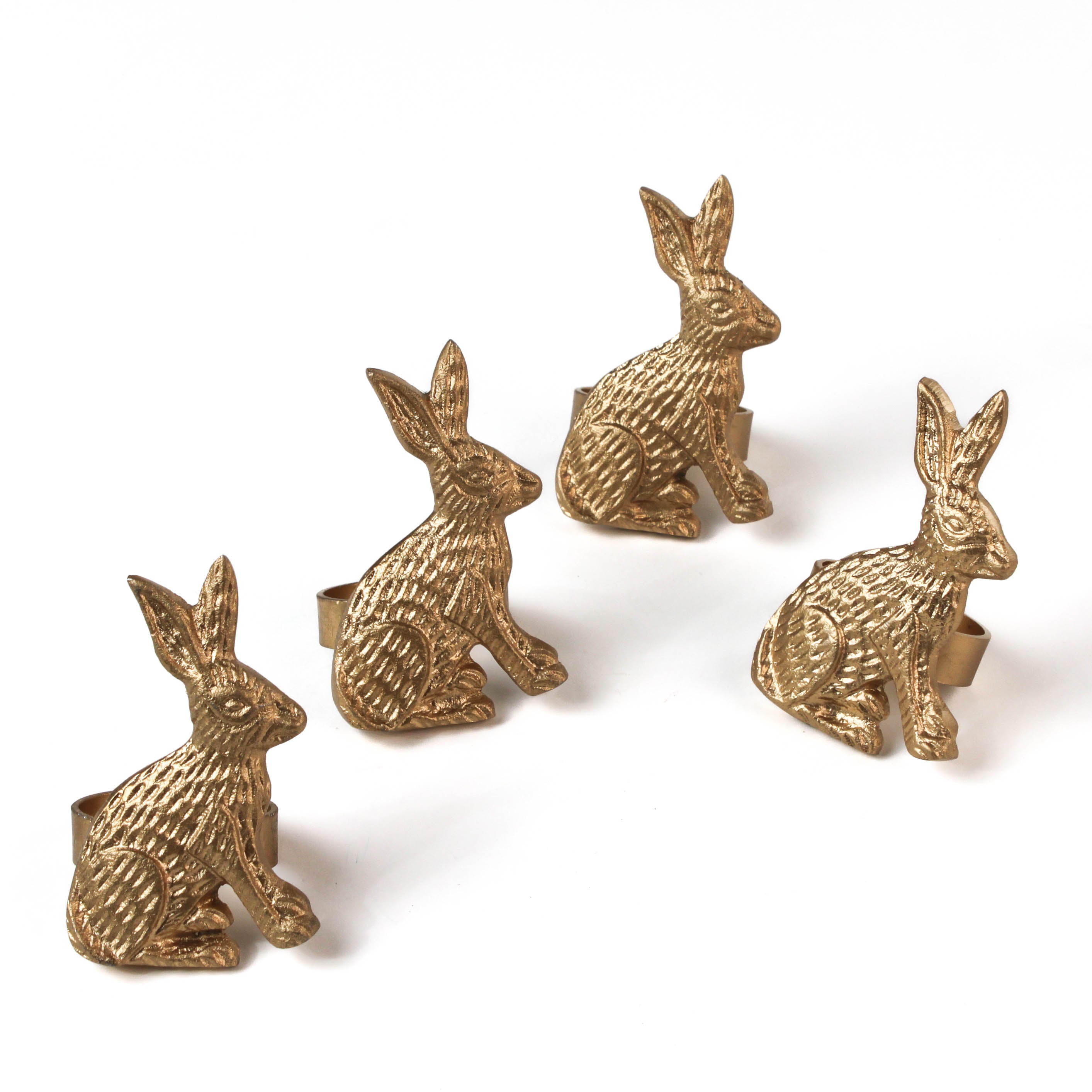 four metal gold bunny napkin rings on a white background. 