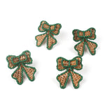Set of four green-trimmed rattan bow napkin rings arranged on a white background.