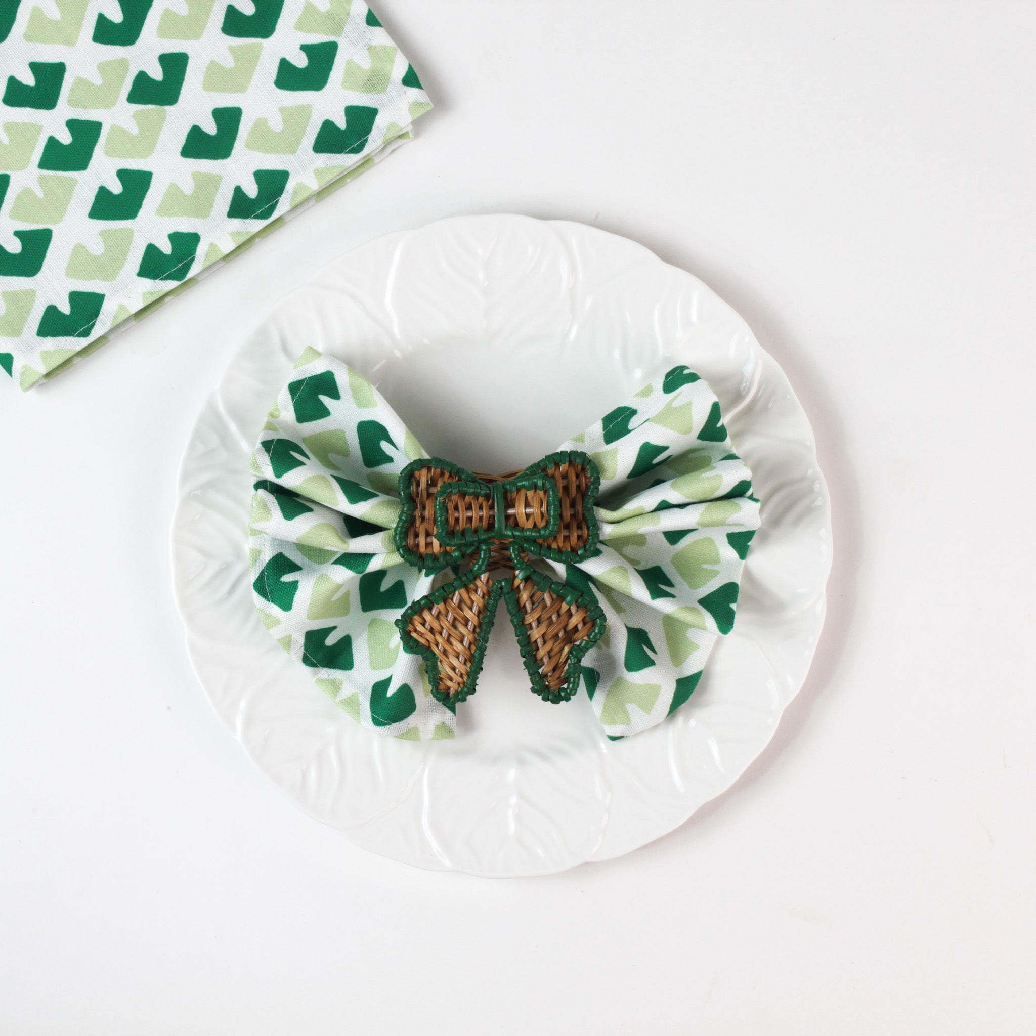 green rattan bow napkin ring on napkin on white plate