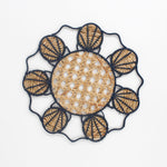 Decorative woven rattan placemat with shell patterns on a white background