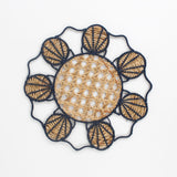 Decorative woven rattan placemat with shell patterns on a white background