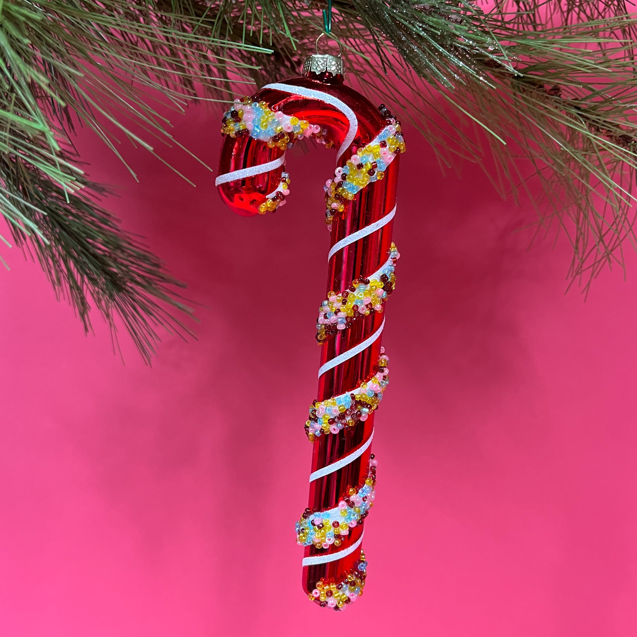 red glass candy cane ornaments on a pink background