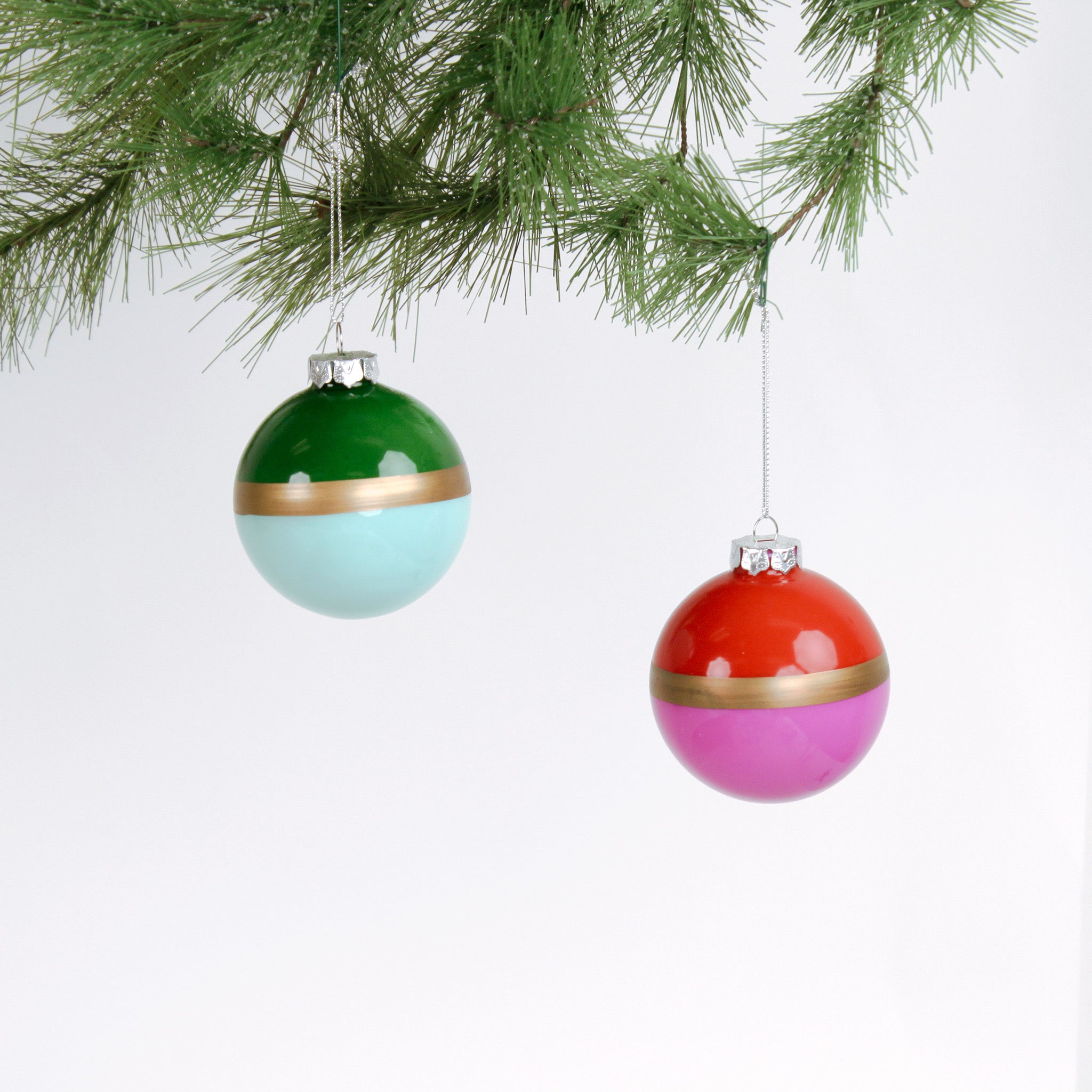 Two colorful Christmas ornaments hanging from a tree branch.
