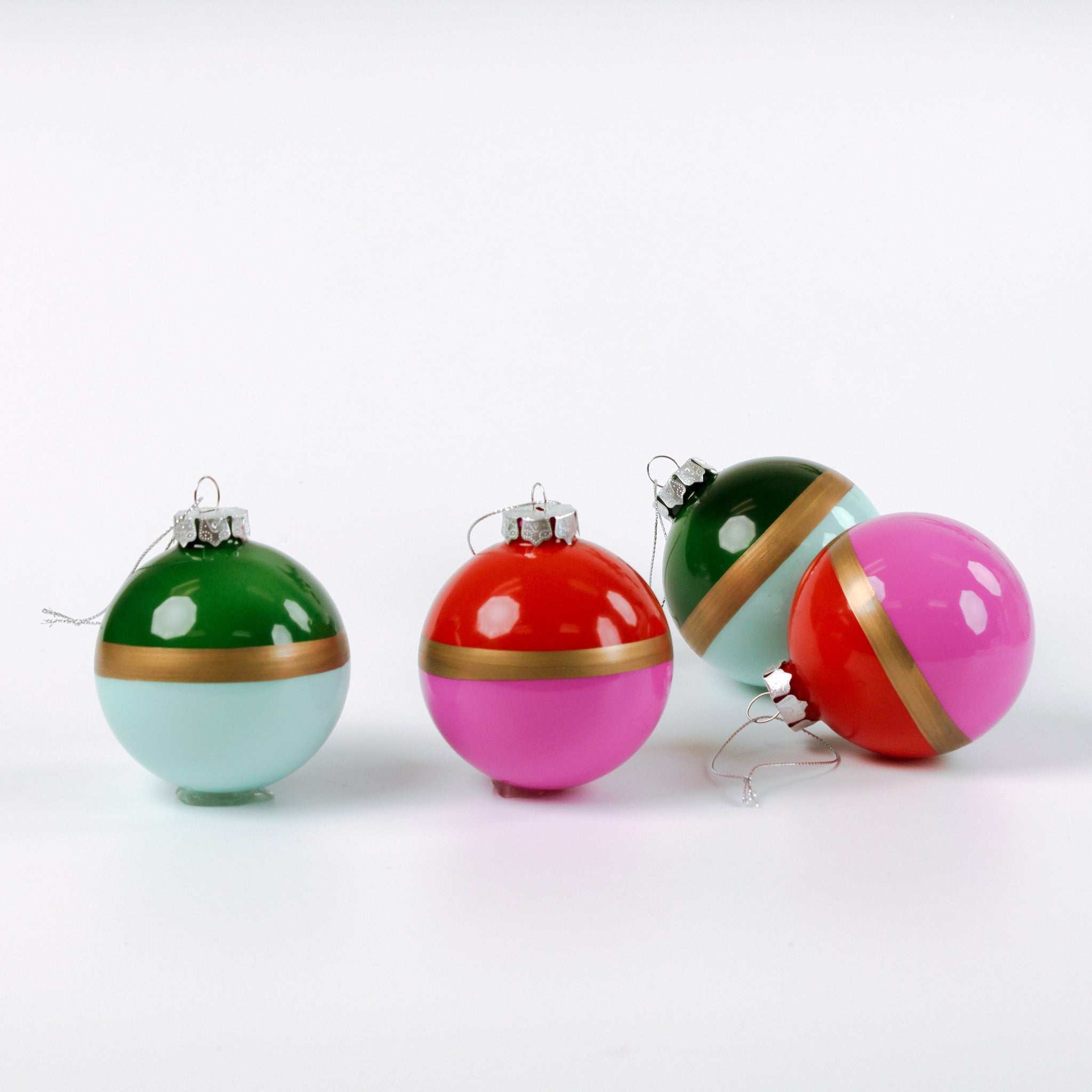 Four colorful Christmas ornaments with gold bands on a white background