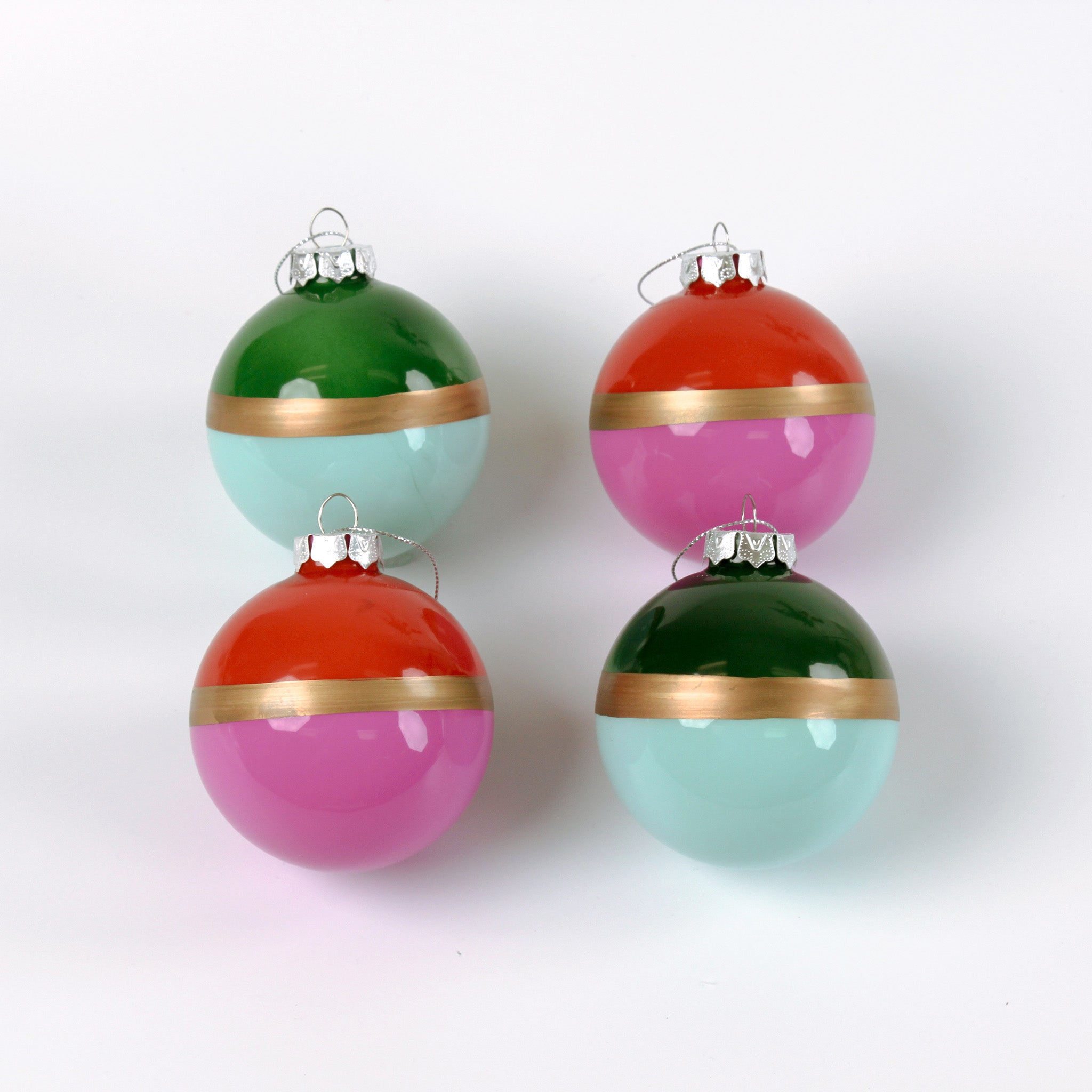 Four colorful Christmas ornaments with gold bands on a white background