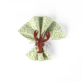 Red lobster napkin ring displayed on a green patterned cloth napkin.