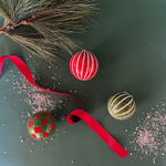 Set of red and green checked and striped christmas ornaments on a green background