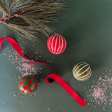 Set of red and green checked and striped christmas ornaments on a green background