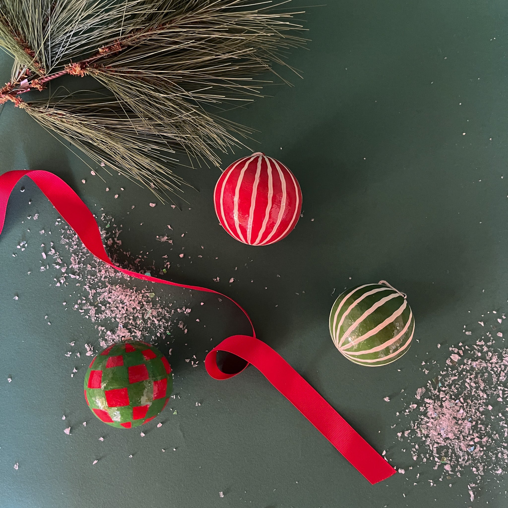 Set of red and green checked and striped christmas ornaments on a green background
