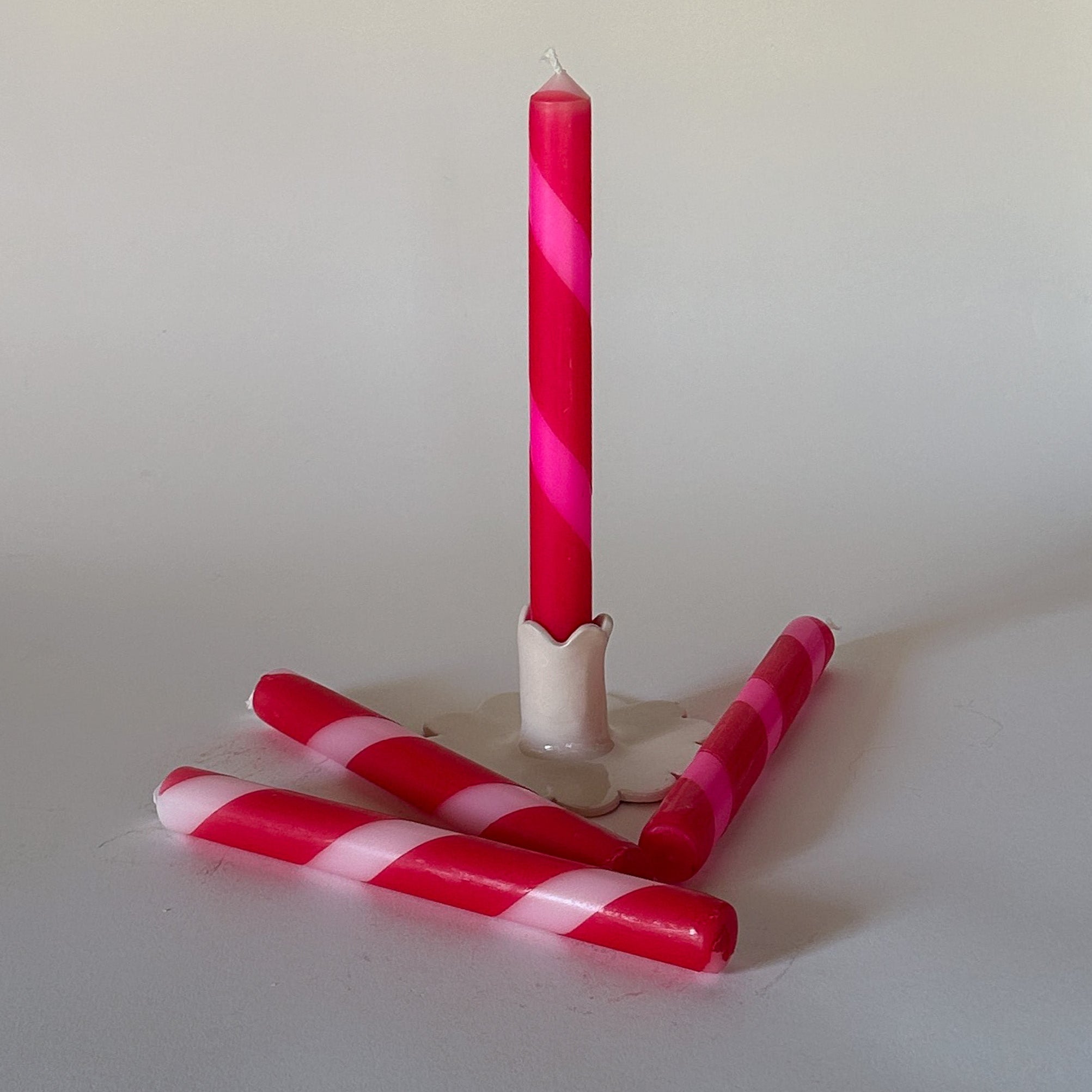 Red Pink Taper Candles with one in a holder and three laying beside