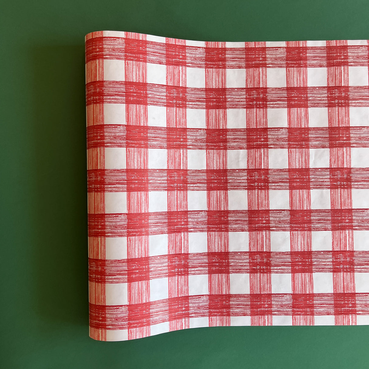 A red gingham paper table runner on a green background. 