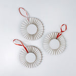 back of three retro-style ruffled paper Christmas ornaments featuring vintage illustrations of a reindeer, Santa in his sleigh, and a snowman, accented with red pleated borders and hanging ribbons
