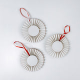 back of three retro-style ruffled paper Christmas ornaments featuring vintage illustrations of a reindeer, Santa in his sleigh, and a snowman, accented with red pleated borders and hanging ribbons