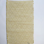 the reverse side of a recycled cotton yellow accent rug with a repeating diamond motif from Madcap Cottage. 