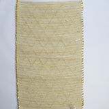 the reverse side of a recycled cotton yellow accent rug with a repeating diamond motif from Madcap Cottage. 