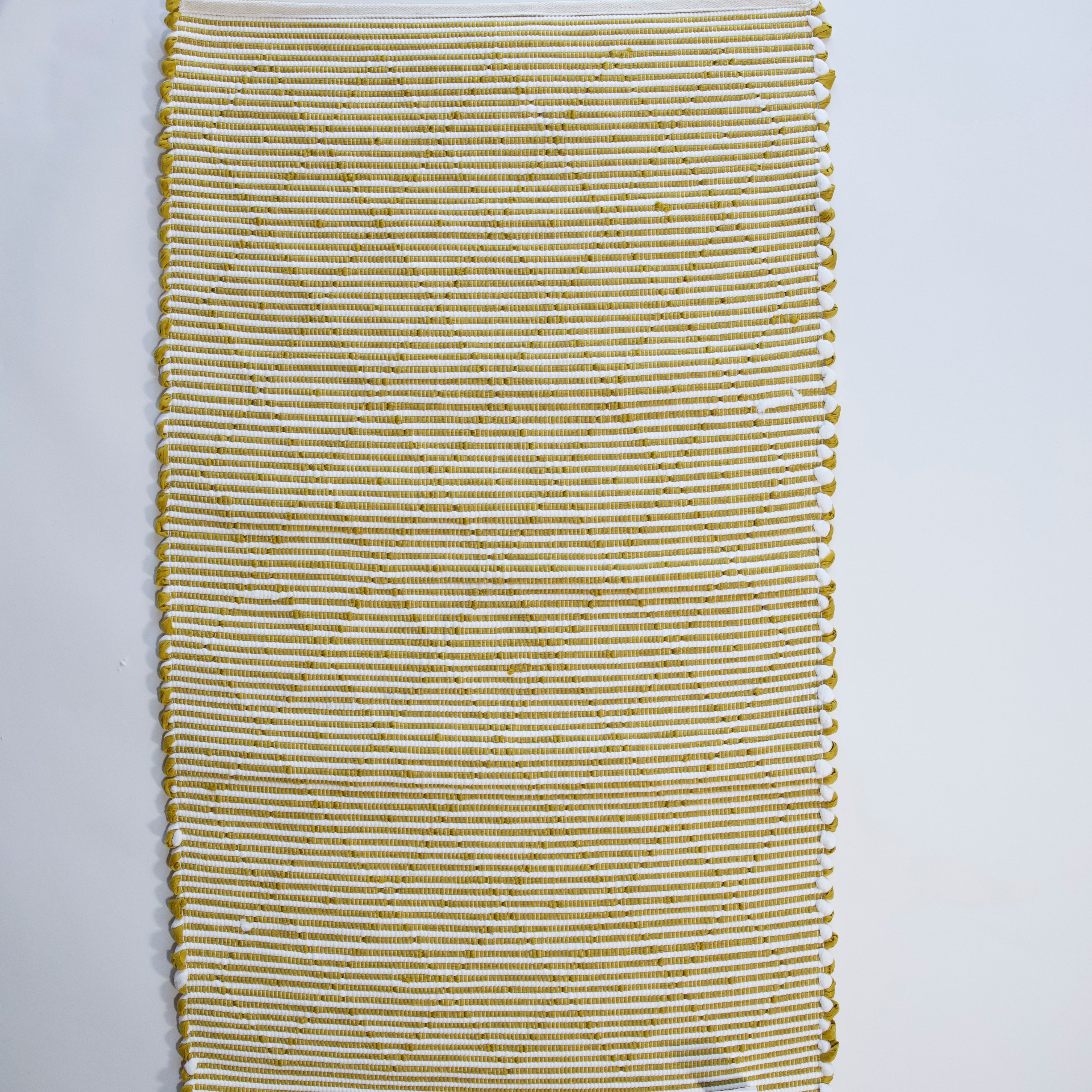 the reverse side of a recycled cotton yellow accent rug with a repeating diamond motif from Madcap Cottage. 