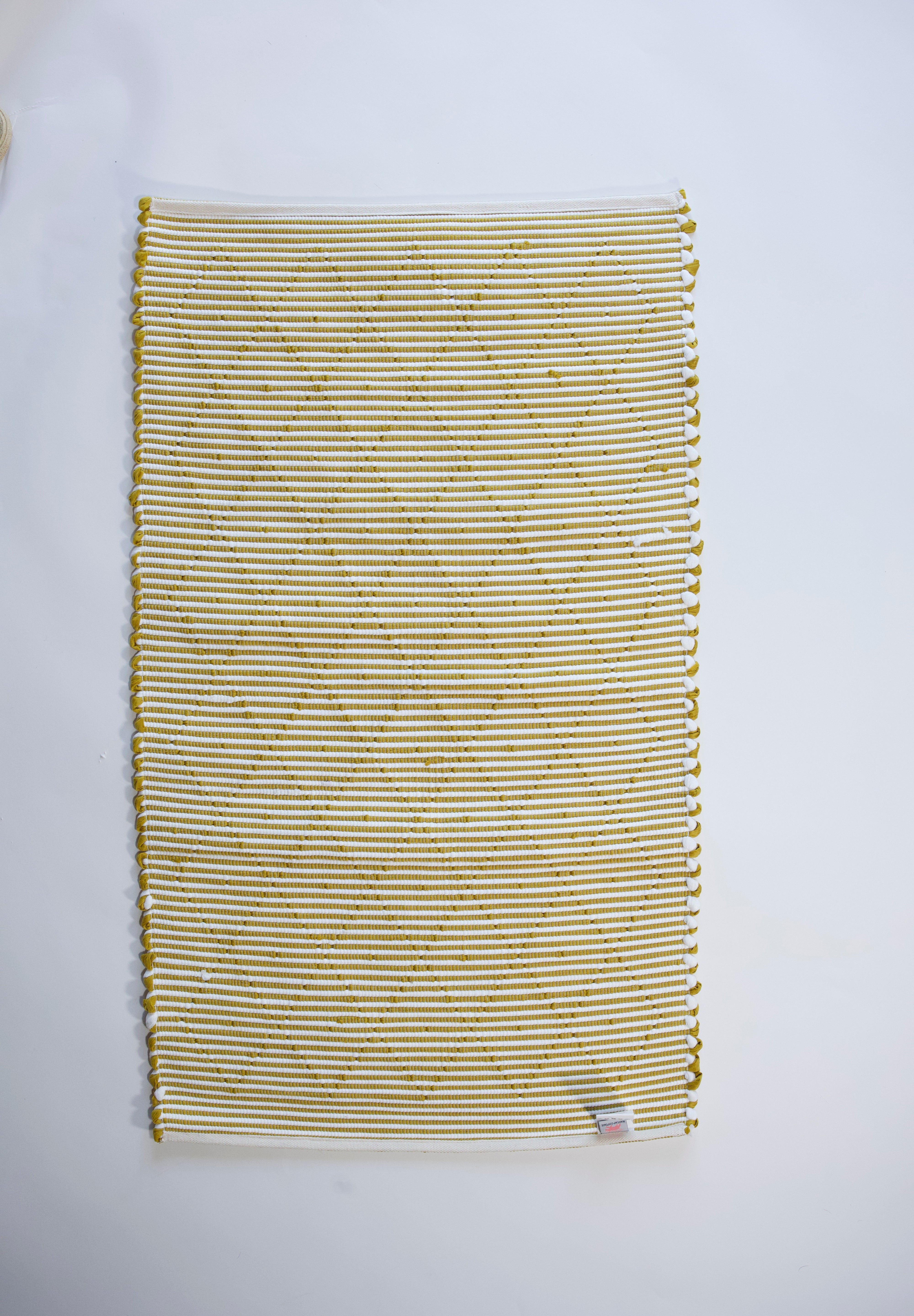 the reverse side of a recycled cotton yellow accent rug with a repeating diamond motif from Madcap Cottage. 