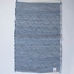the reverse side of a cotton blue accent rug with a repeating diamond motif from Madcap Cottage. 
