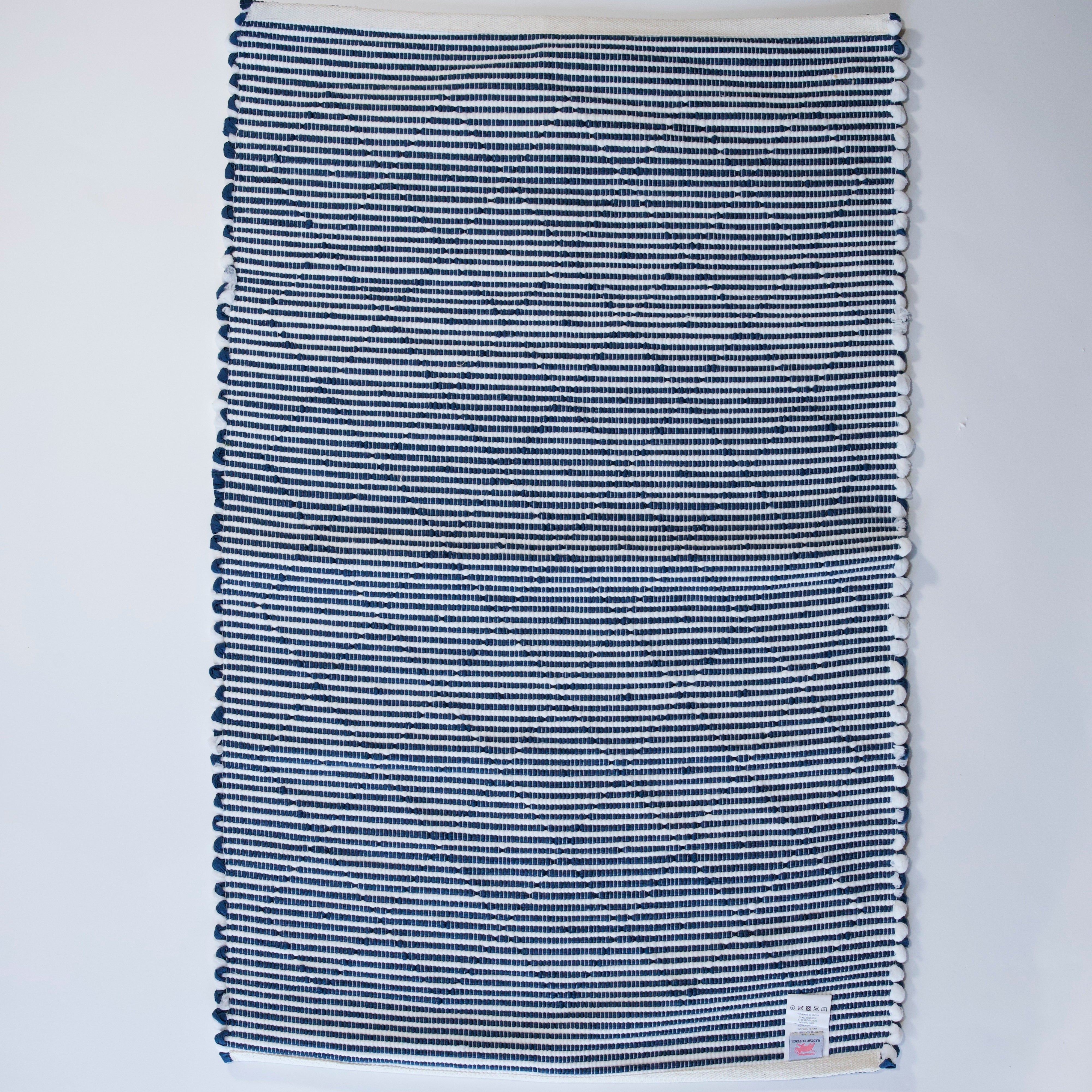 the reverse side of a cotton blue accent rug with a repeating diamond motif from Madcap Cottage. 