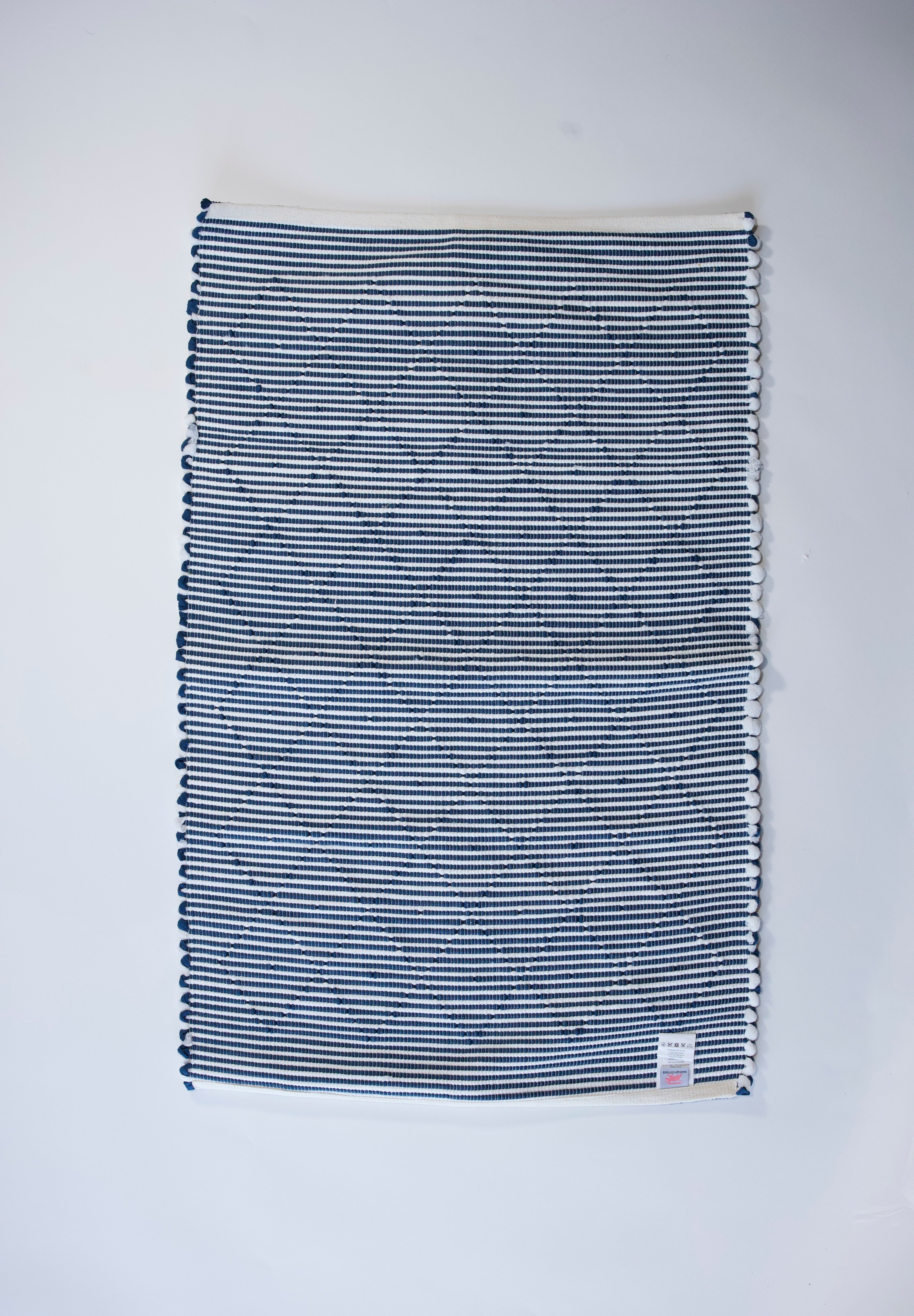 the reverse side of a cotton blue accent rug with a repeating diamond motif from Madcap Cottage. 