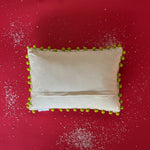reverse side of a white, pom-pom trimmed hooked-wool christmas pillow featuring a central pagoda motif flanked by two christmas trees