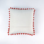 Reverse white side of a christmas pillow with red pom-pom trim on a white background