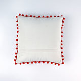 Reverse white side of a christmas pillow with red pom-pom trim on a white background