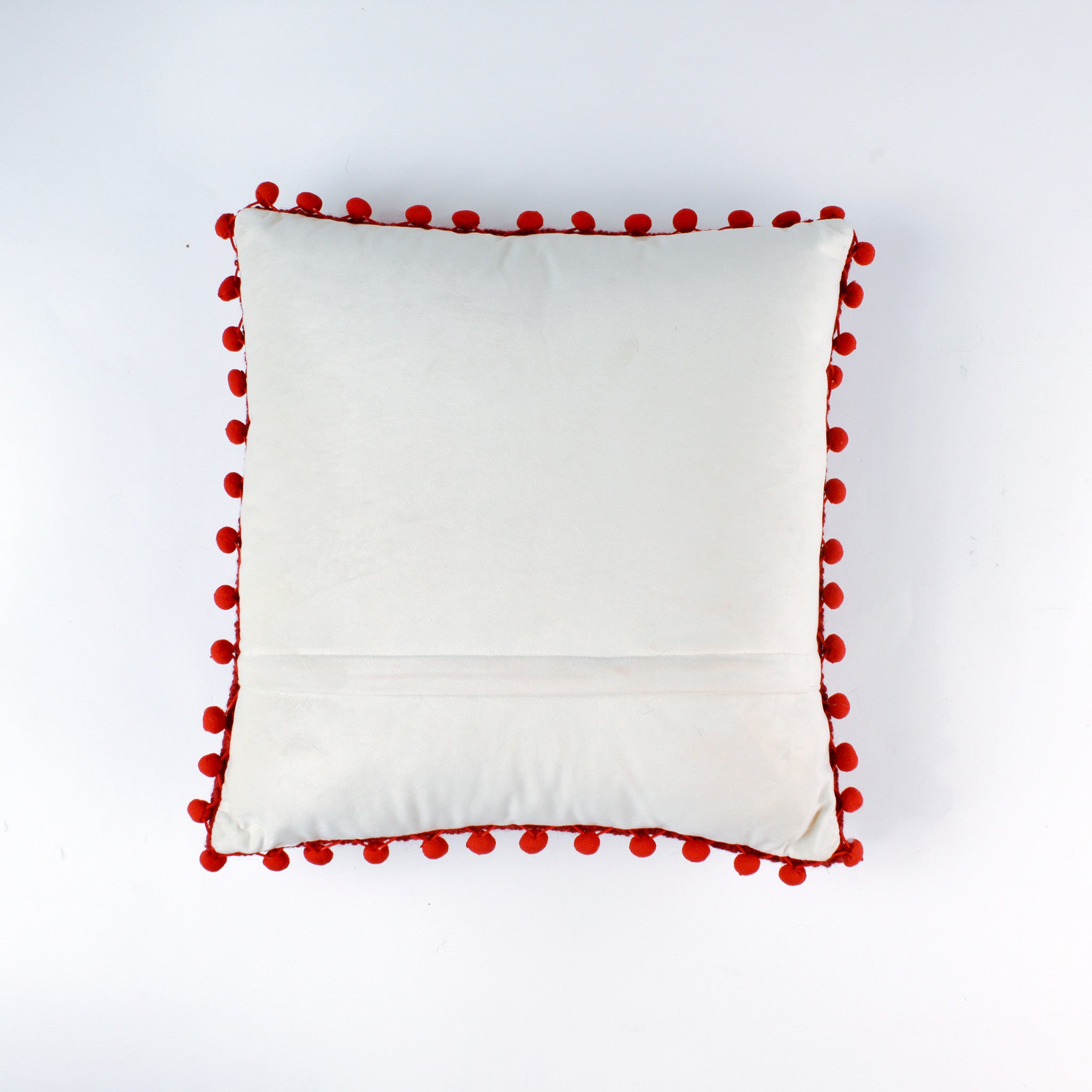 Reverse white side of a christmas pillow with red pom-pom trim on a white background