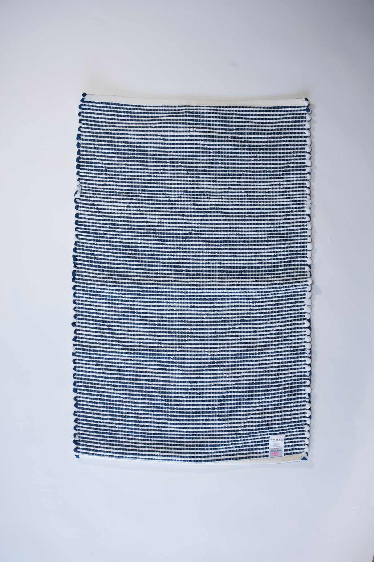the reverse side of a cotton blue accent rug with a repeating diamond motif from Madcap Cottage. 