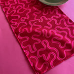 Ribbons Dark Pink and Red No-Iron cloth Table Runner on a pink background