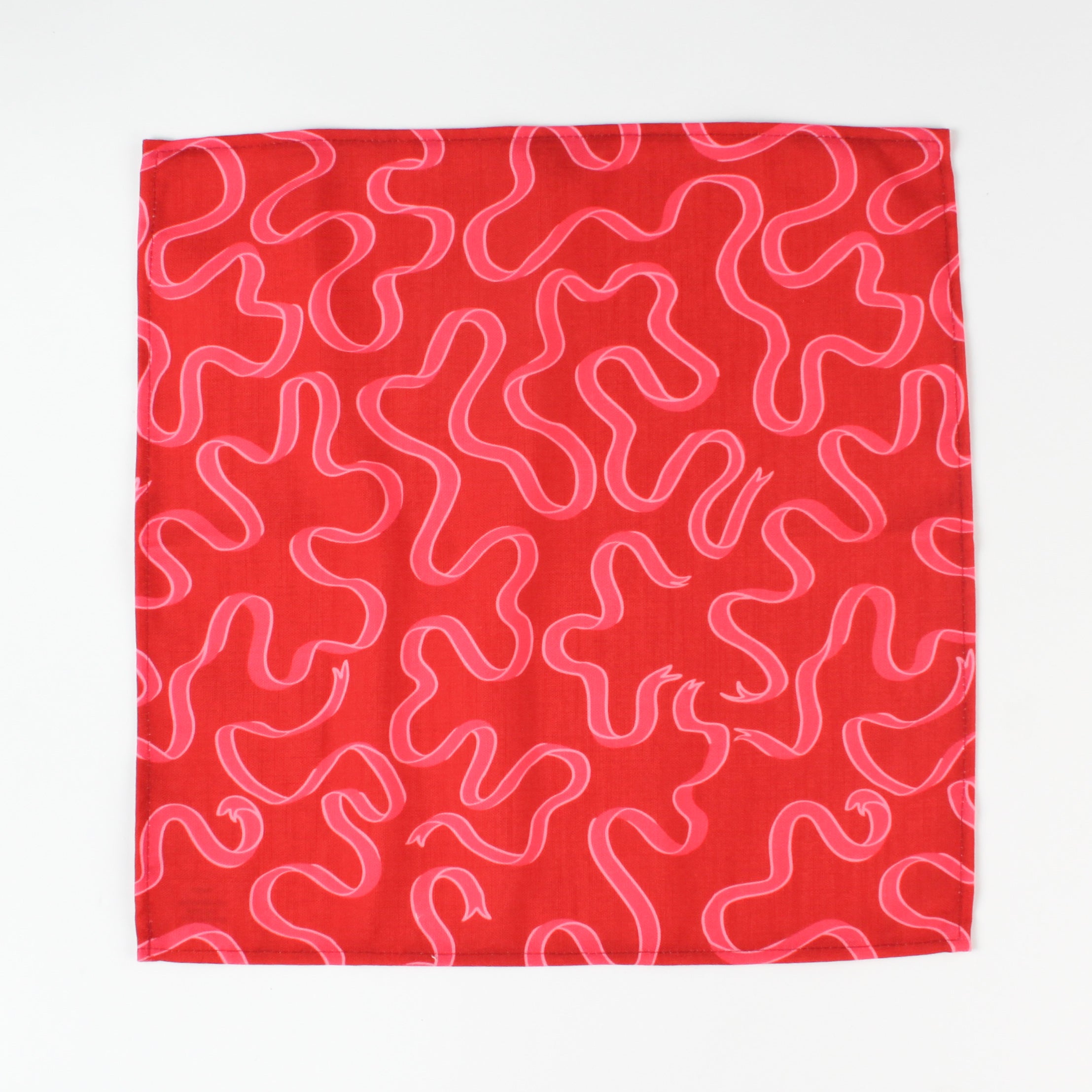 Red and pink ribbon-print Christmas tea towel napkin folded to show inside lining, made in USA fabric