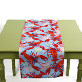 Blue table runner featuring a red lobster and seashell pattern displayed on a green table.