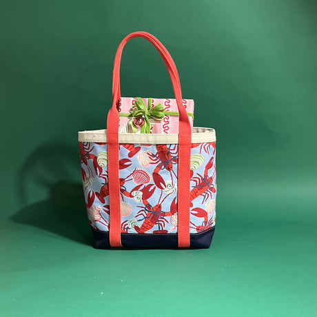 Rock Lobster large canvas tote bag with red straps and blue fabric with a repeating lobster and shell motif.